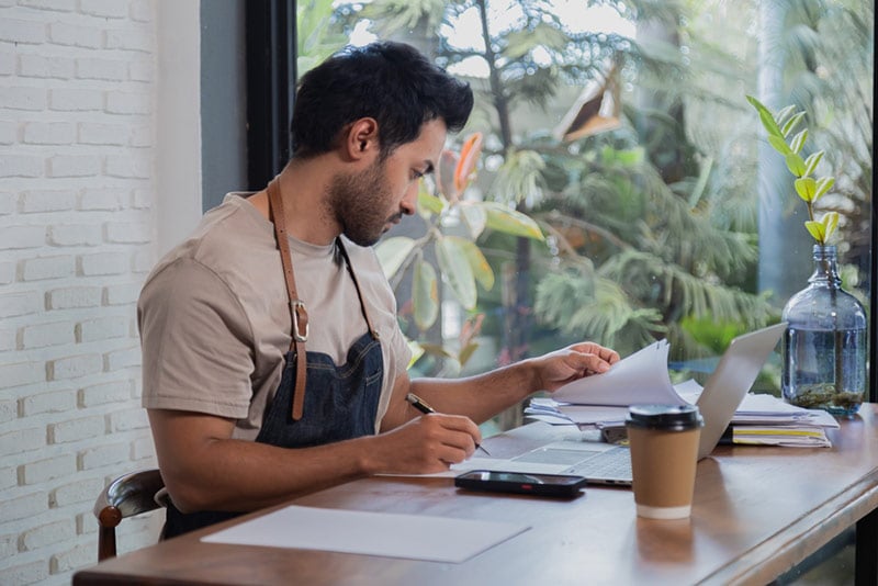 Café owner examining financial documents for taxes
