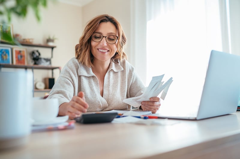 Woman with glasses examining taxes documents with calculator