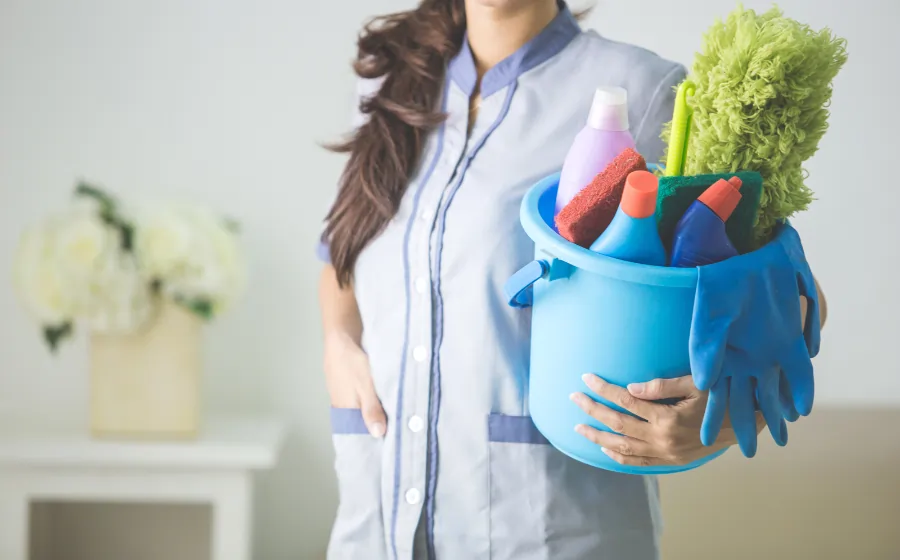 housemaid holding a bucket with cleaning products inside