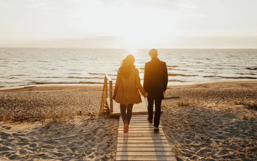 couple walking holding hands towards the beach
